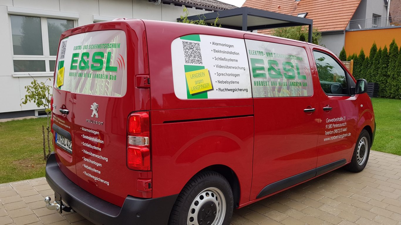 Roter Lieferwagen mit Werbung für einen Dienstleister auf der Seite.