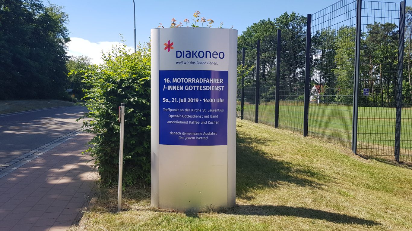 Schild mit Informationen zur Einrichtung und den Nutzungsregeln an einem Sportplatz.
