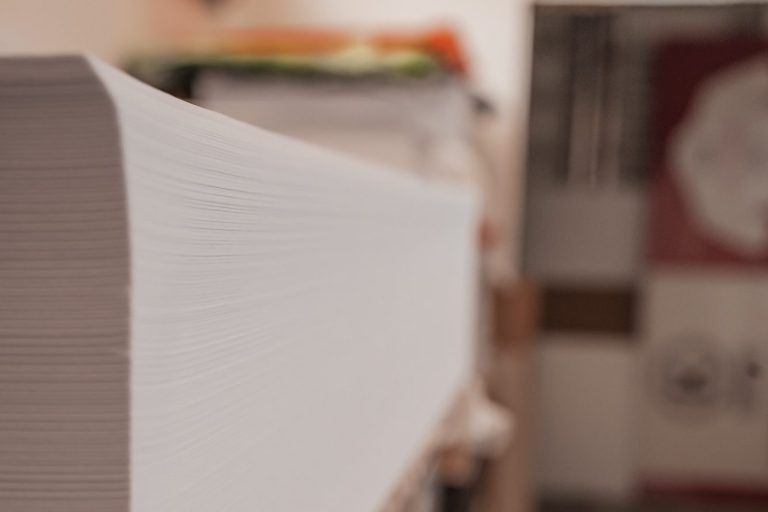 Nahaufnahme eines Stapels weißer Papierblätter auf einem Tisch.