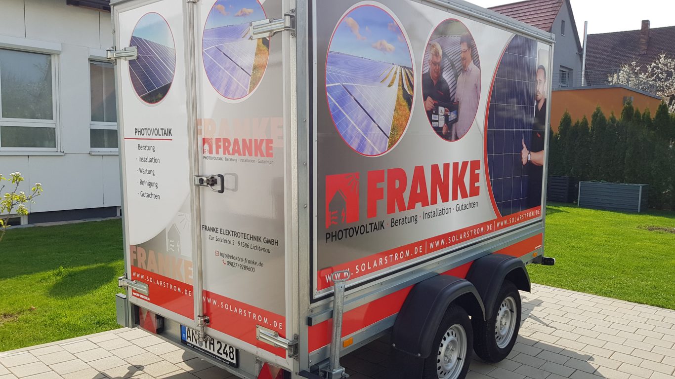 Werbefahrzeug mit grauer Plane, beschriftet mit dem Namen "Franke" und Bildern.