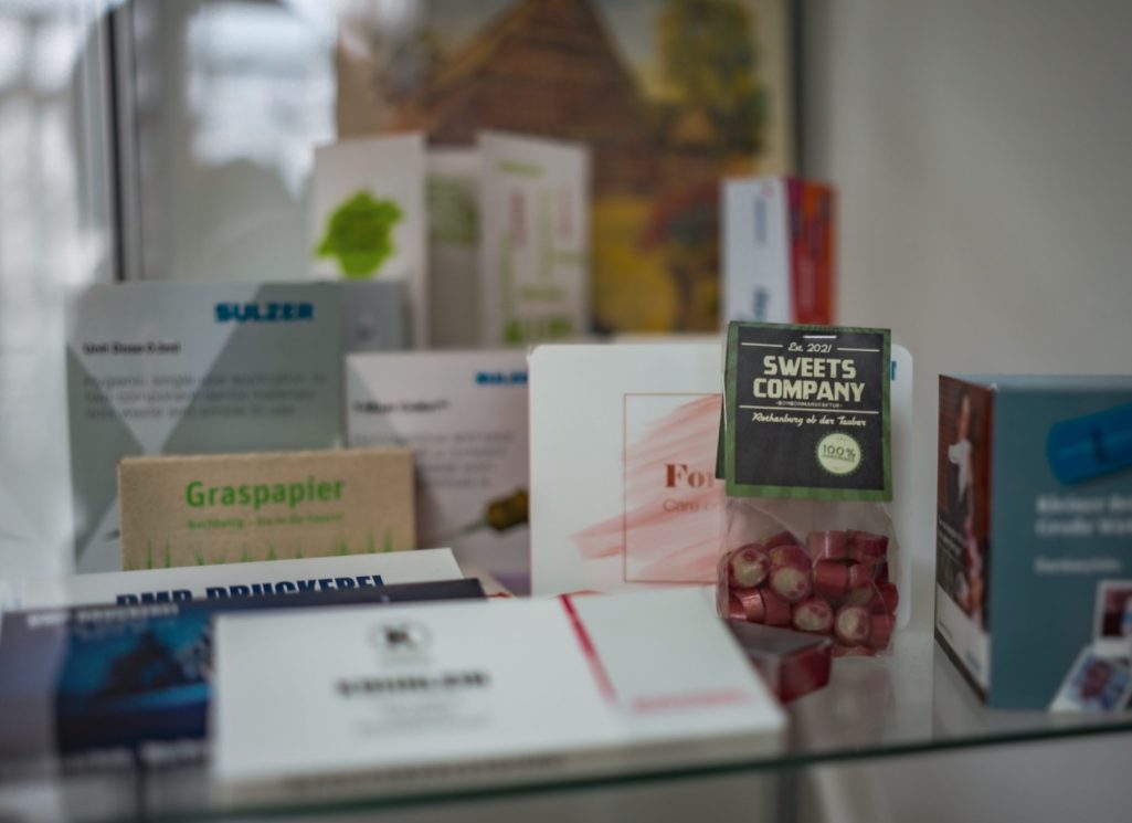 Verschiedene Verpackungen in einem Regal, überwiegend in neutralen Farben.