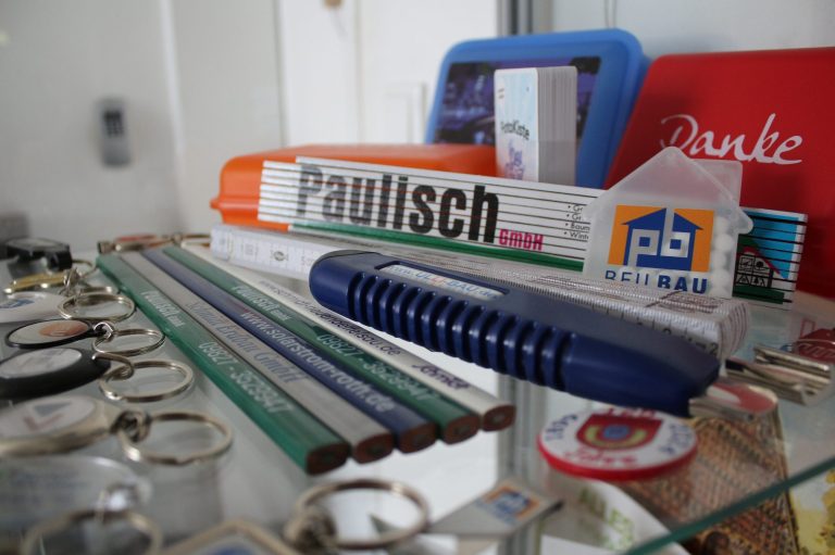 Büroartikel und Schreibwaren auf einem Tisch, darunter ein Metermaß und ein blaues Kattermesser.