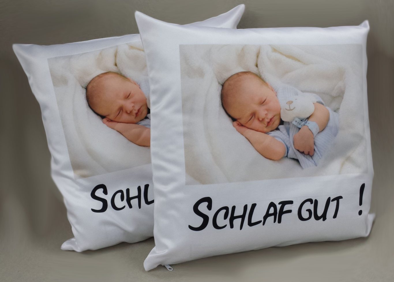 Zwei Kissen mit einem lächelnden Baby und dem Text "SCHLAFGUT!"