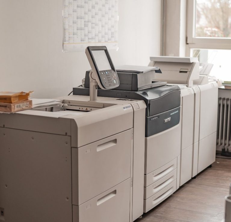 Bürodrucker und Kopierer stehen nebeneinander in einem hellen Raum.