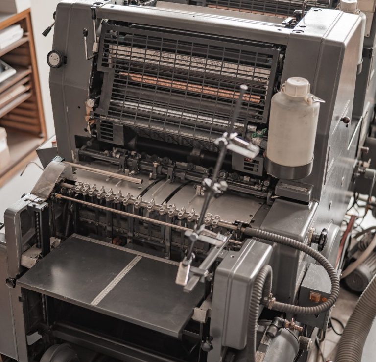 Alte Druckmaschine mit mechanischen Komponenten und Tasten eingestellt auf einer Arbeitsfläche.