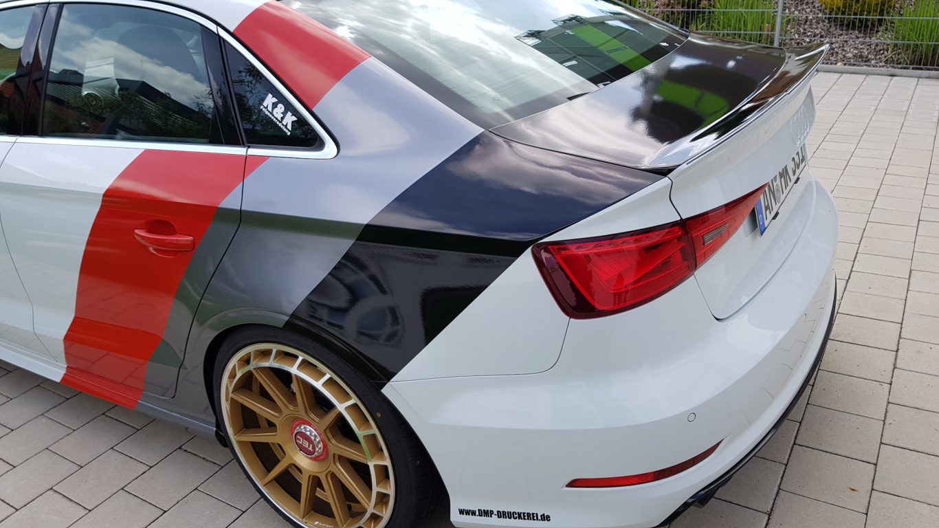 Auto mit auffälliger, mehrfarbiger Lackierung und goldenen Felgen.