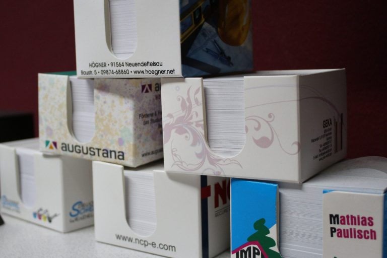 Gestapelte Boxen mit verschiedenen Designs und Farben auf einem roten Hintergrund.